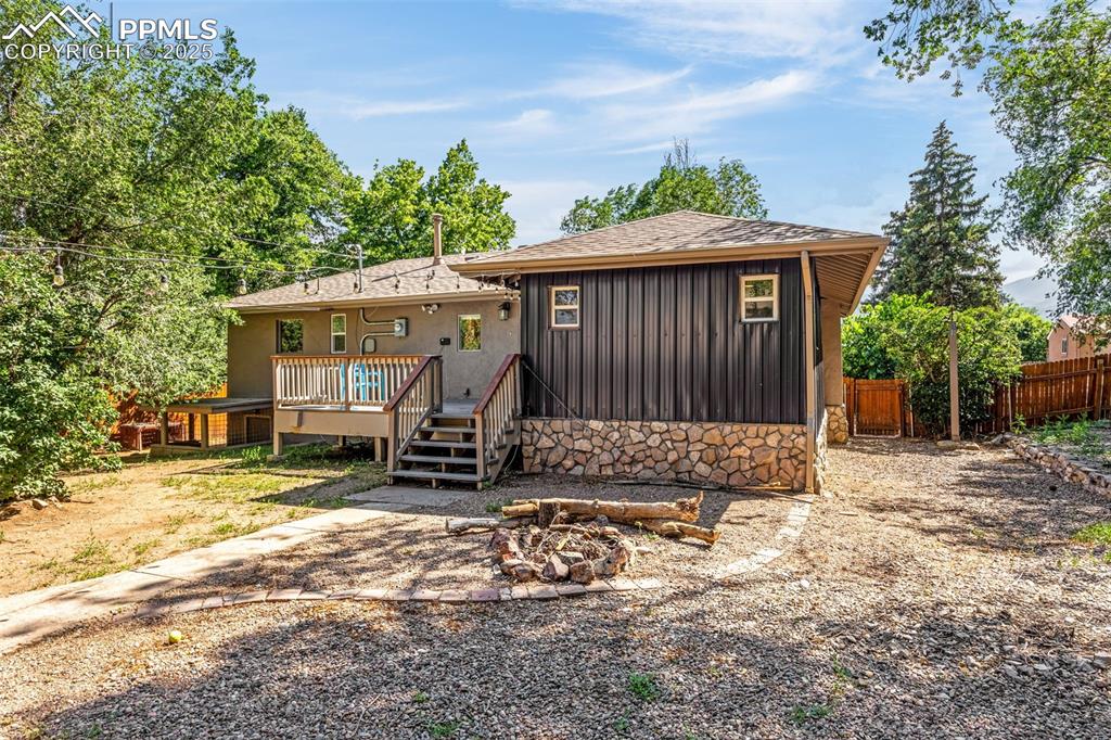 Image 33 of 42: Back of property with an outdoor fire pit, a deck, and a shingled roof