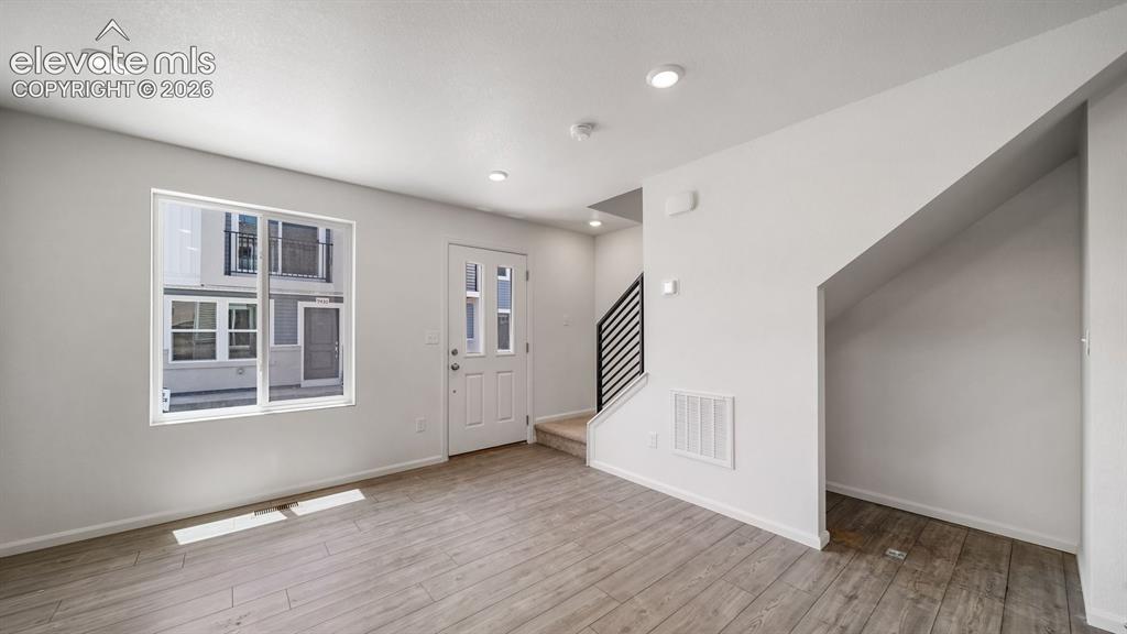 Image 10 of 17: Recessed lighting, wood-finish flooring, white paneled entry door, white tr