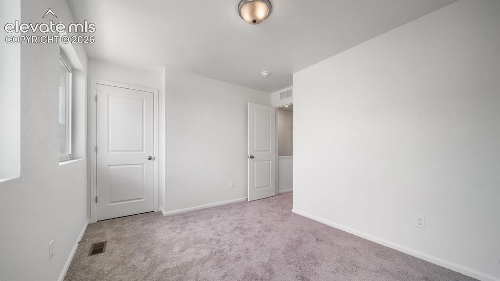 Image 2 of 17: Neutral tone wall paint, neutral tone carpet, white trim throughout, window