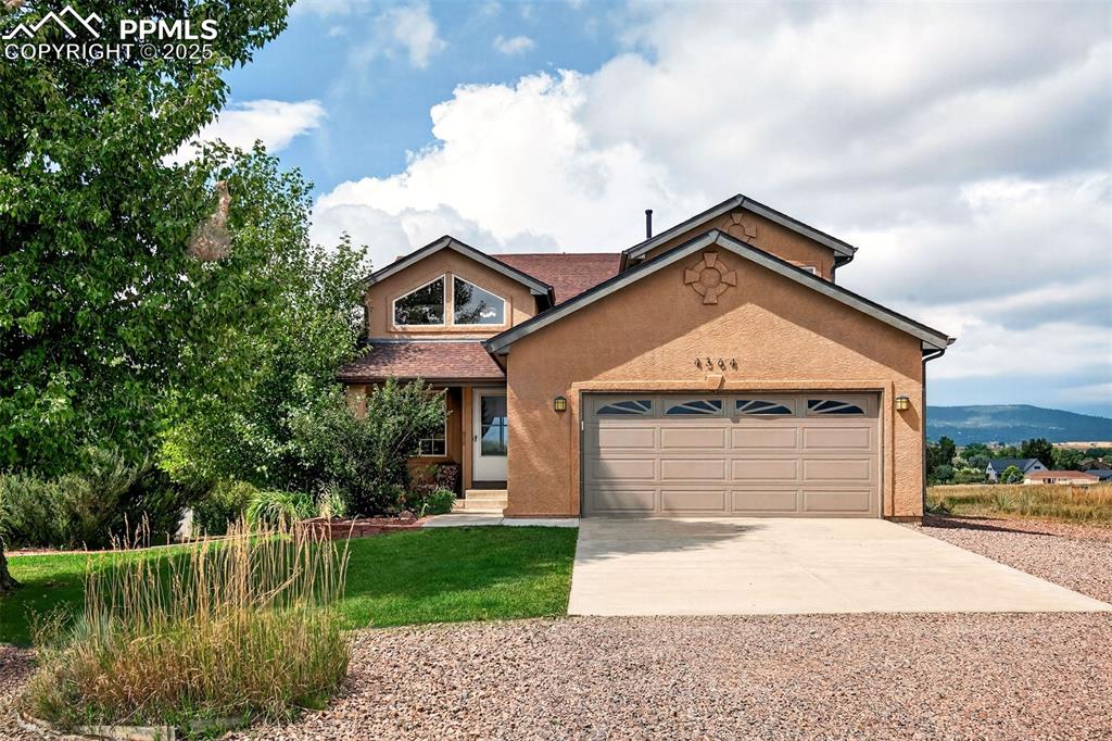 Caption: View of front of house featuring concrete driveway, stucco siding, an attached garage, a front yard,