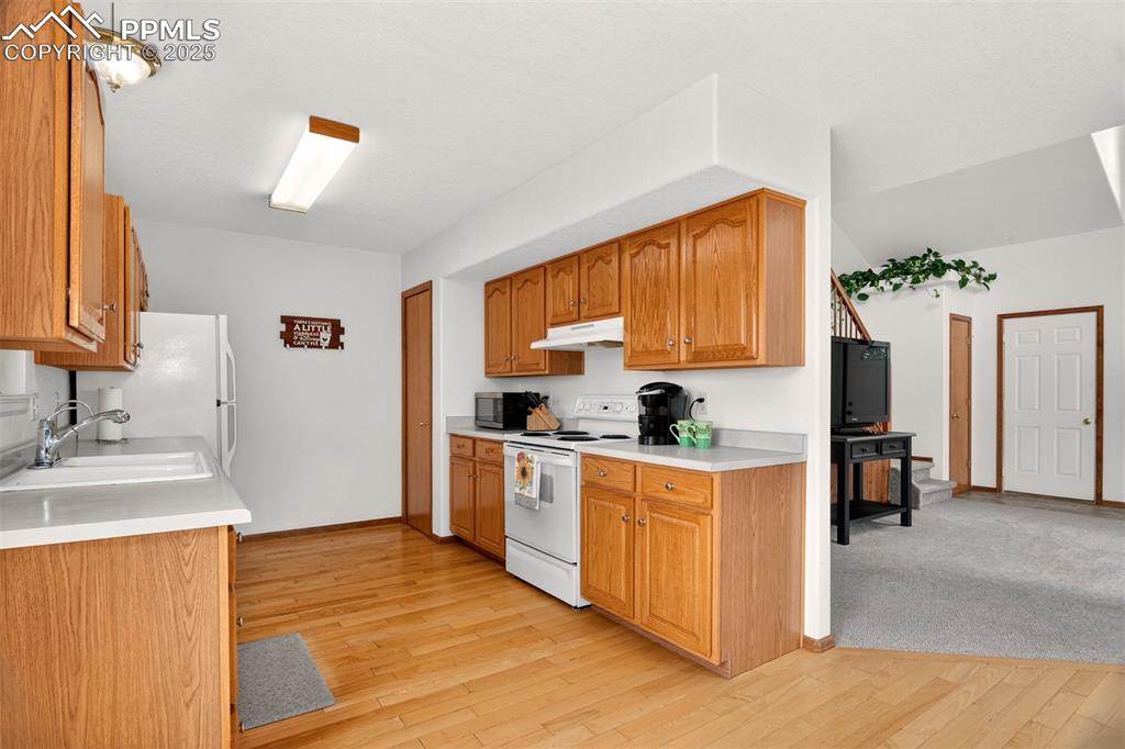 Image 10 of 40: Kitchen with white appliances, light wood-style flooring, light countertops