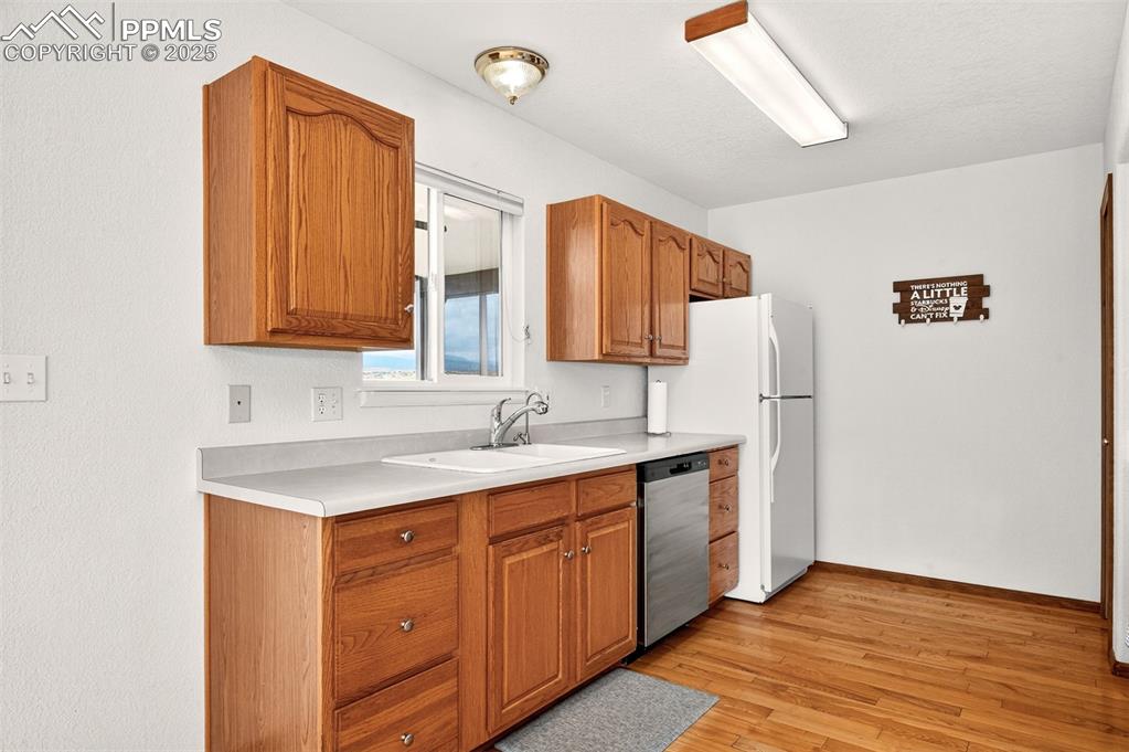 Image 11 of 40: Kitchen with light countertops, brown cabinets, light wood-style flooring,