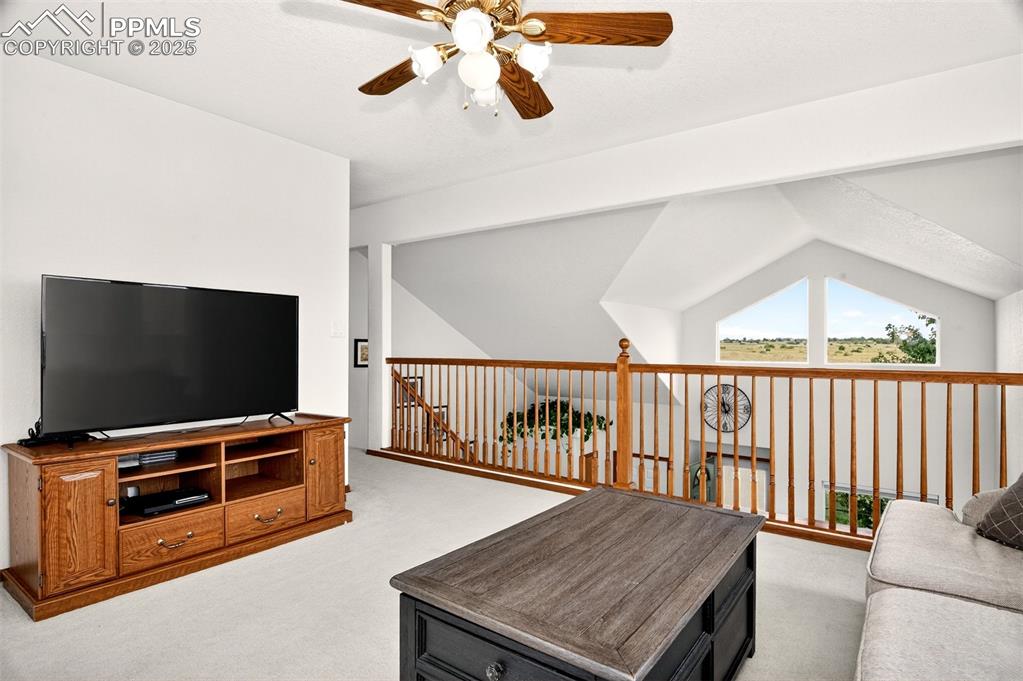 Image 17 of 40: Upstairs loft featuring light carpet, a ceiling fan, and lofted ceiling