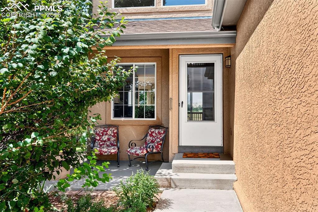 Image 2 of 40: Property entrance with stucco siding and roof with shingles