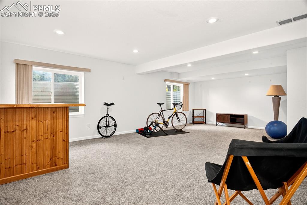 Image 24 of 40: Downstairs Exercise area with beam ceiling, light colored carpet, and reces