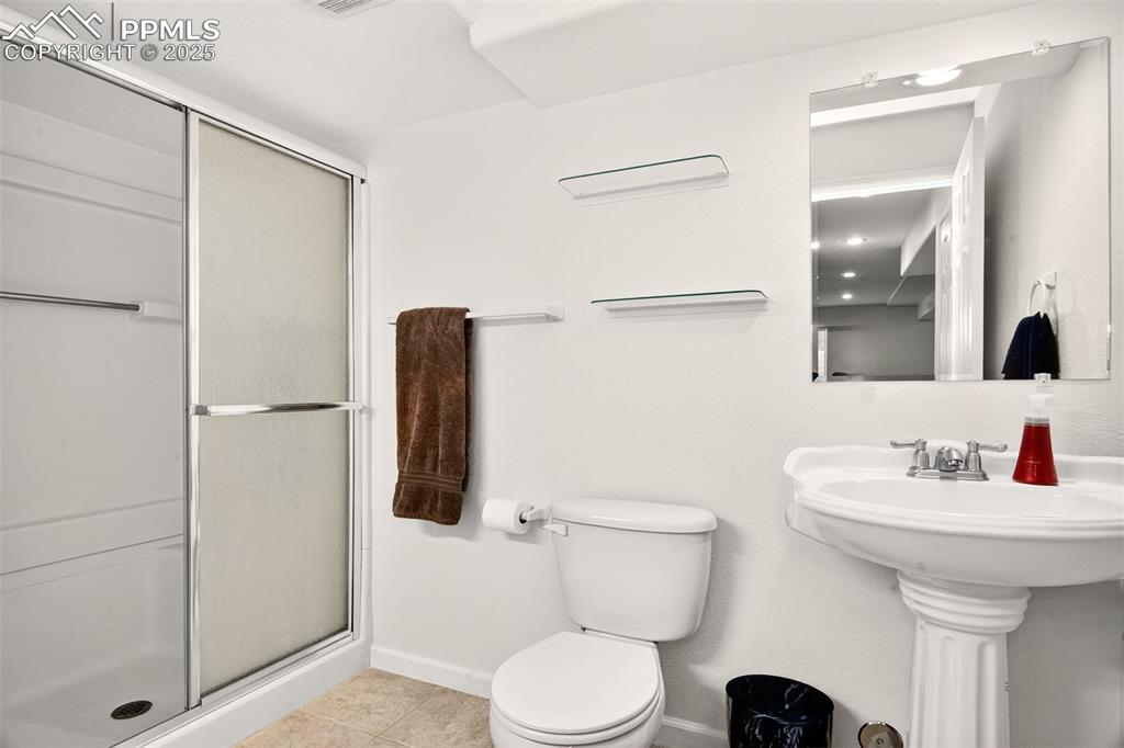 Image 28 of 40: Bathroom with light tile patterned floors and a stall shower