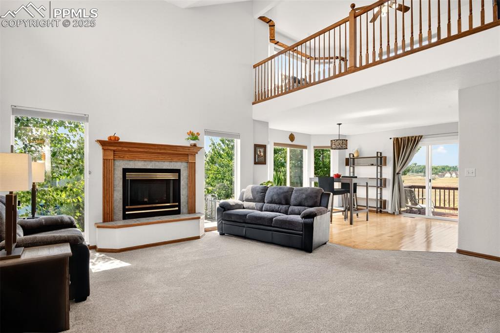 Image 3 of 40: Living room featuring a towering ceiling, carpet, a tiled fireplace, and ce