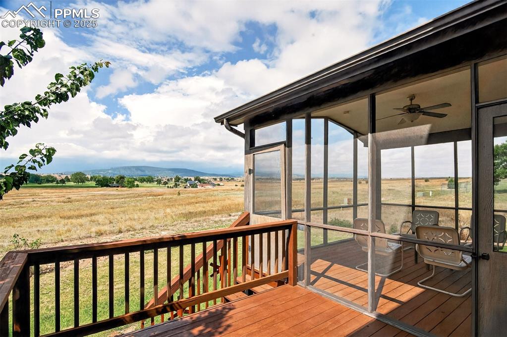 Image 30 of 40: Deck featuring a sunroom, a rural view, ceiling fan, and a yard