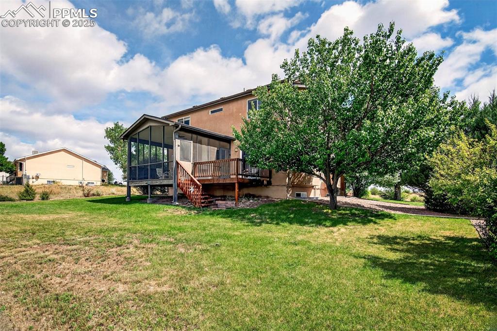 Image 33 of 40: View of green lawn featuring a sunroom, a wooden deck, and stairs