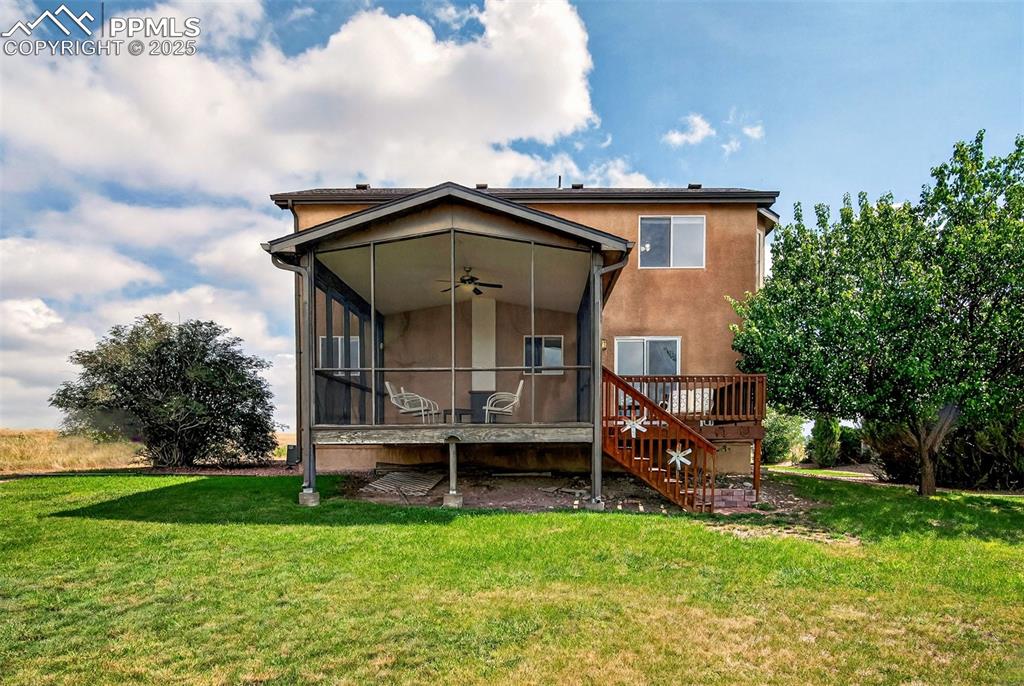 Image 35 of 40: Rear view of house featuring ceiling fan, a sunroom, a lawn, and a wooden d