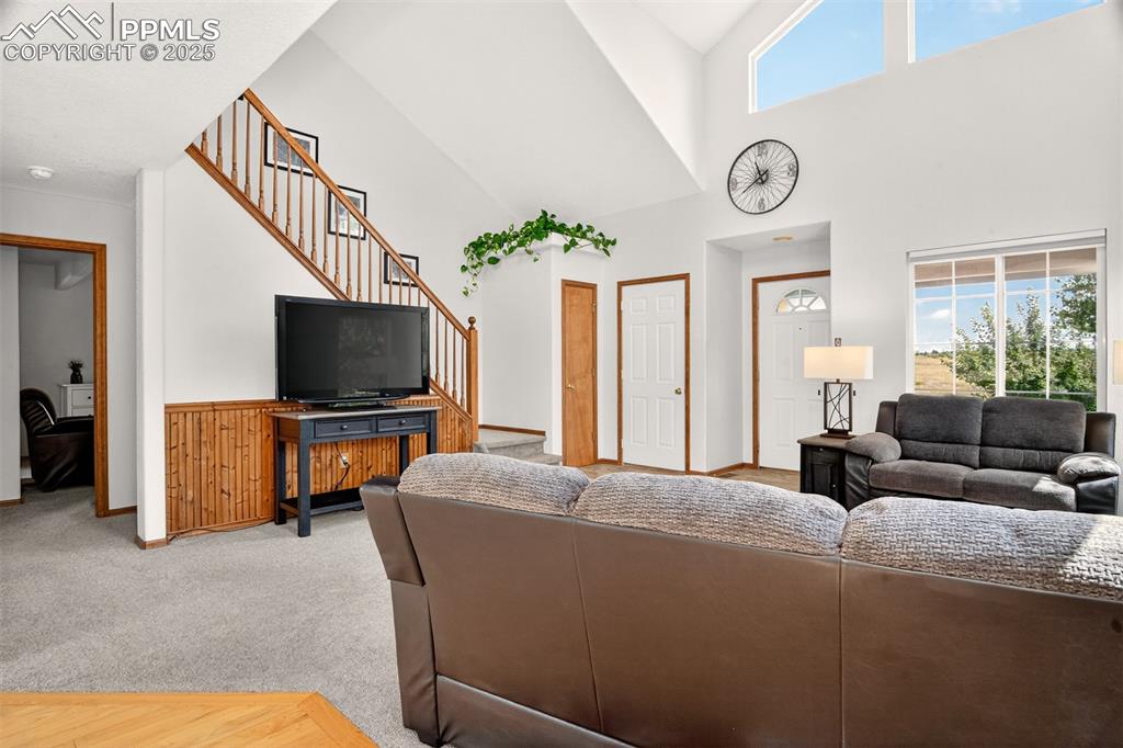Image 4 of 40: Carpeted living area with plenty of natural light, stairs, and a high ceili
