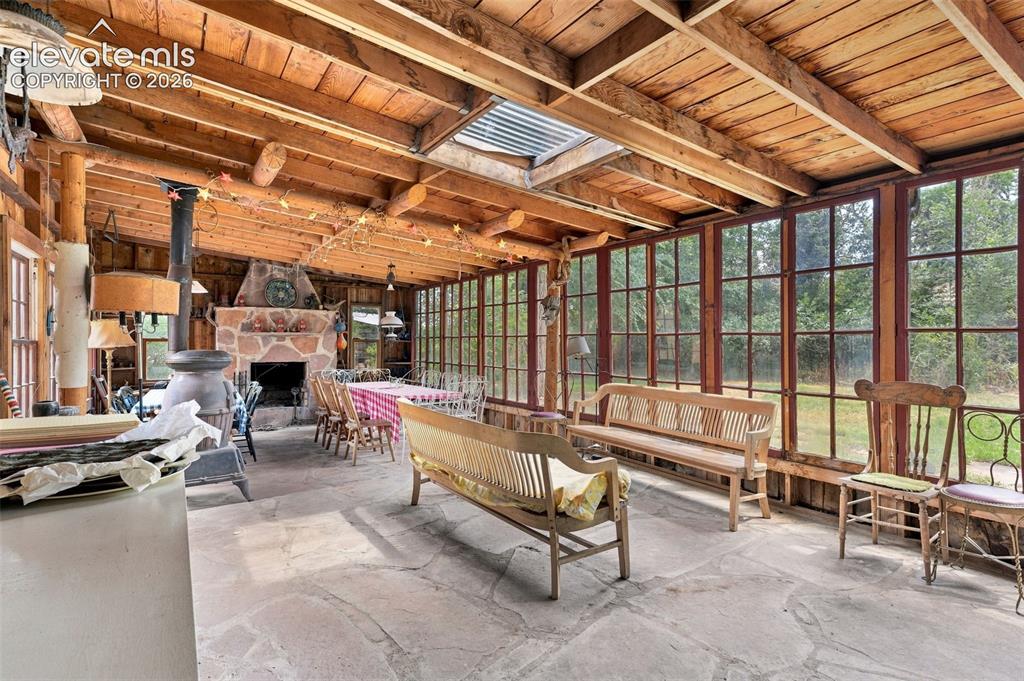 Image 42 of 50: Enclosed porch with flagstone floors and large wood burning fireplace
