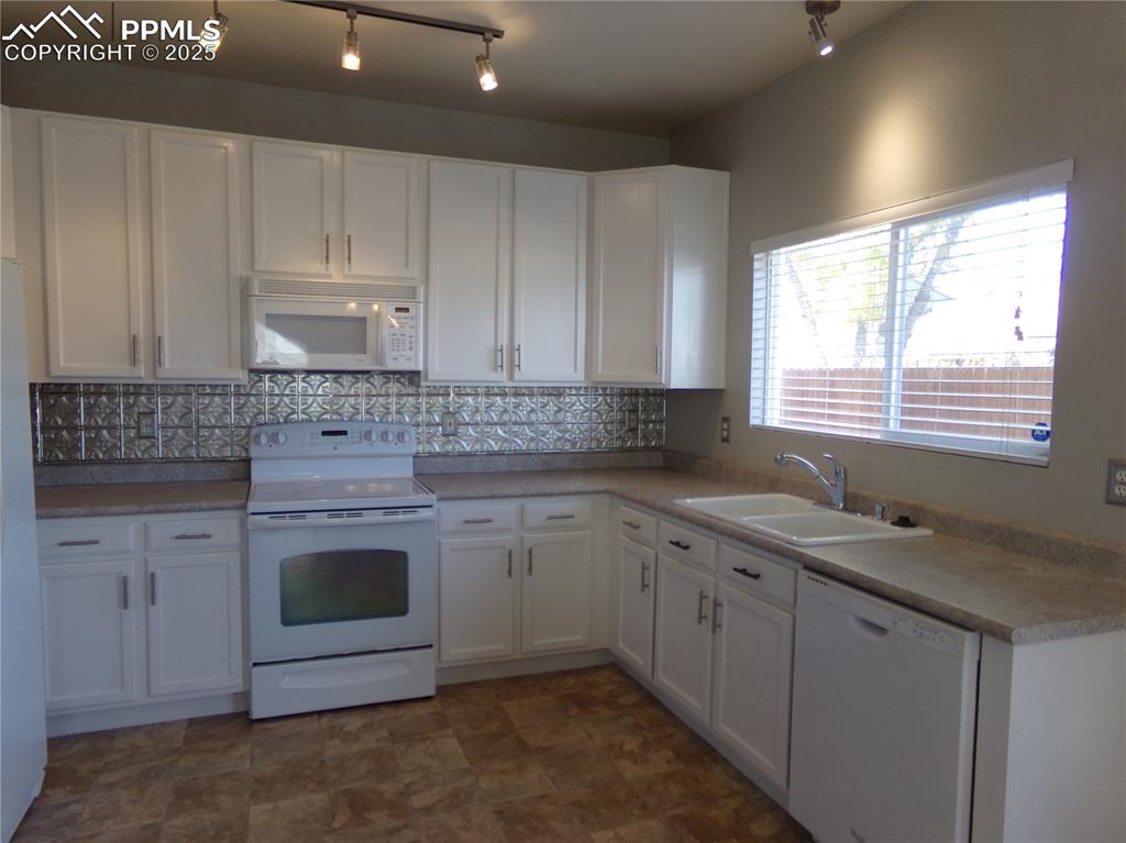 Image 10 of 29: Kitchen with white cabinetry, white appliances, and backsplash