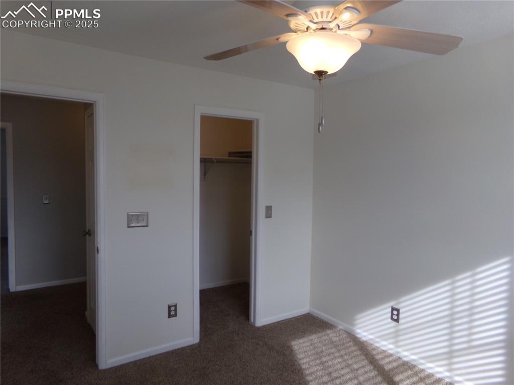 Image 22 of 29: Unfurnished bedroom with carpet floors, a ceiling fan, and a walk in closet