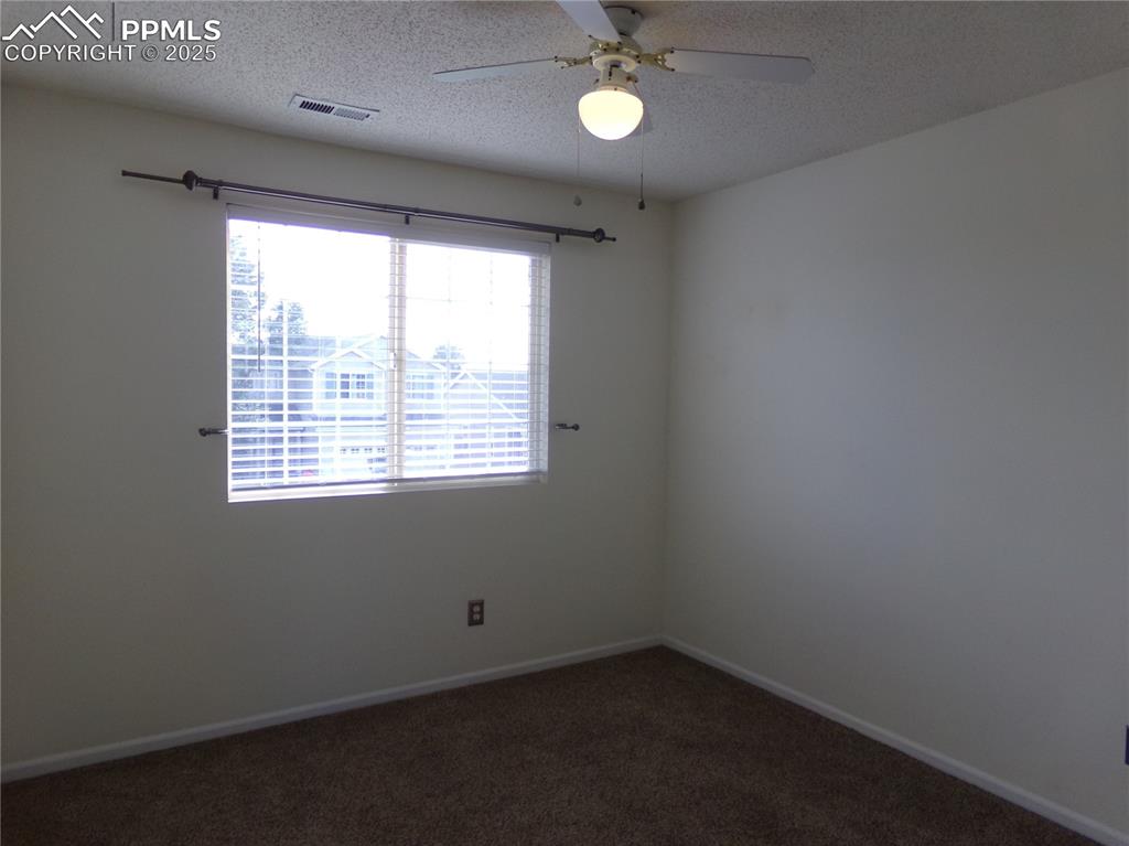 Image 23 of 29: Unfurnished room featuring dark colored carpet, a textured ceiling, and a c