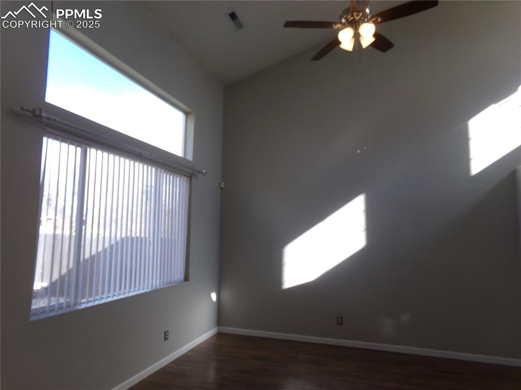 Image 5 of 29: Empty room featuring dark wood-type flooring, vaulted ceiling, and a ceilin