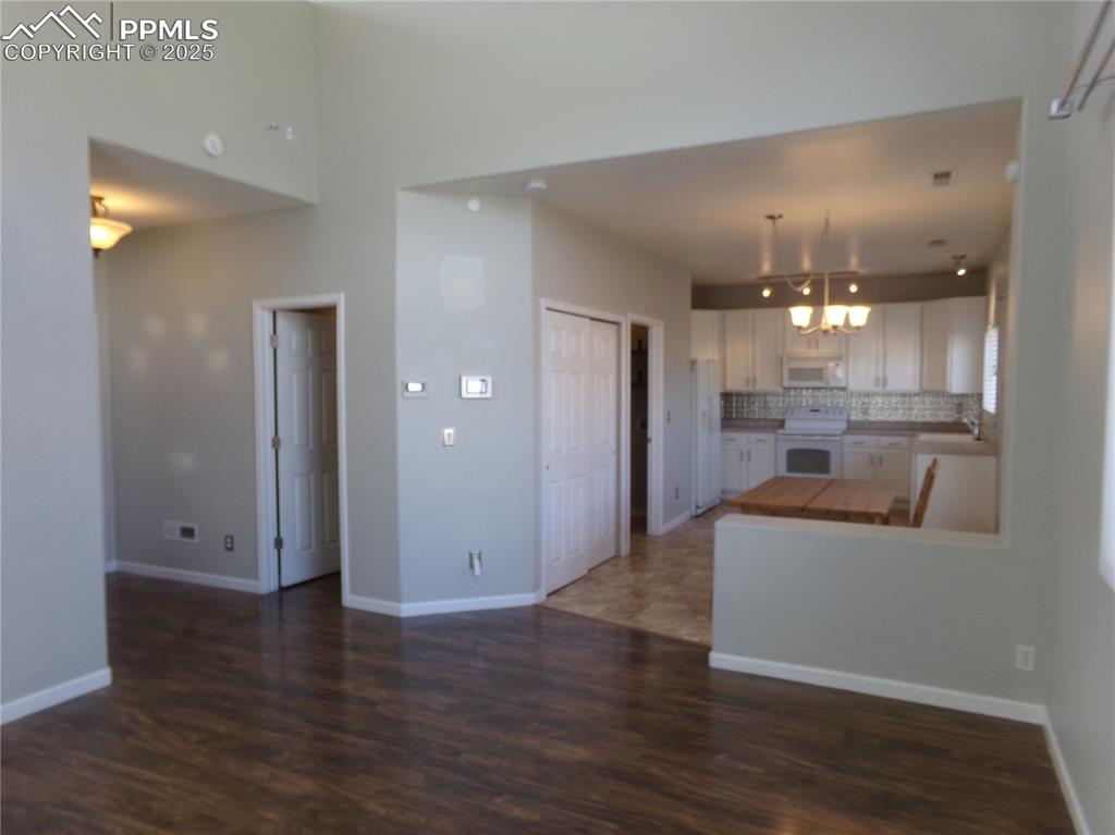 Image 7 of 29: Kitchen with white cabinets, tasteful backsplash, white appliances, dark wo