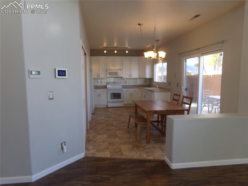 Image 8 of 29: Kitchen with tasteful backsplash, white cabinets, white appliances, light w