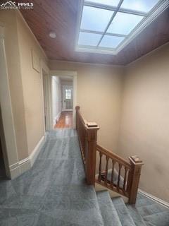 Image 15 of 50: Hall with dark colored carpet, an upstairs landing, and wood ceiling