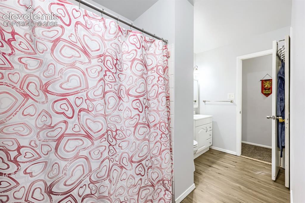 Image 13 of 26: Wood-finish flooring with light wall tones and white baseboards