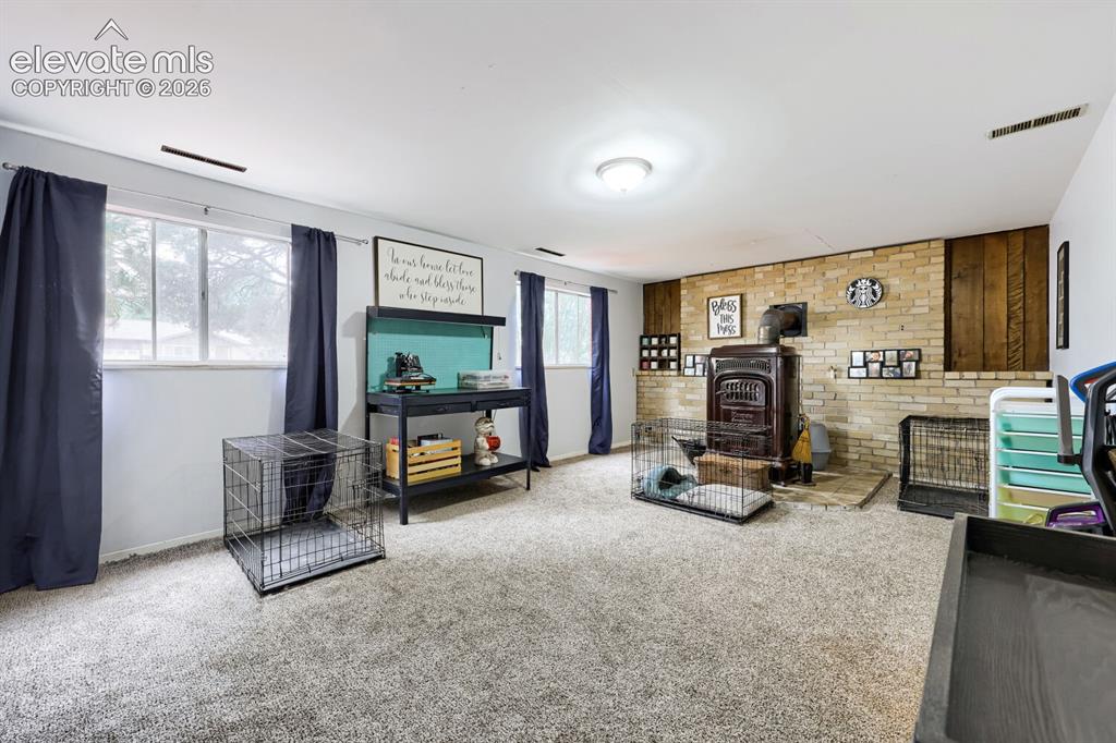 Image 18 of 26: Carpeted flooring, multiple windows, brick accent wall, wood paneling, and