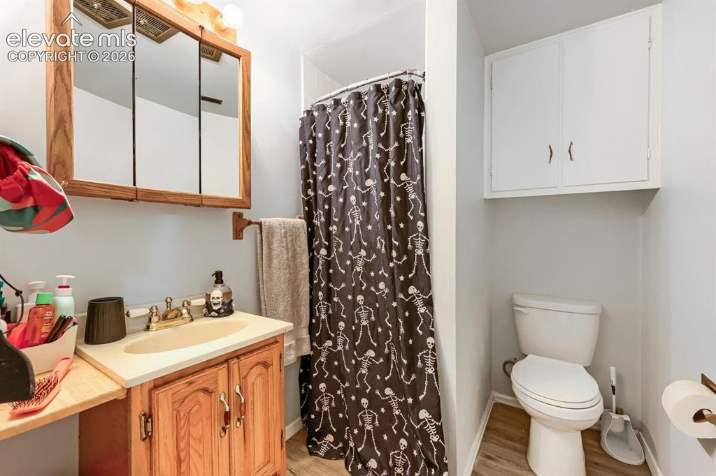 Image 23 of 26: Wood-finish vanity with a built-in sink, wall-mounted medicine cabinet, whi