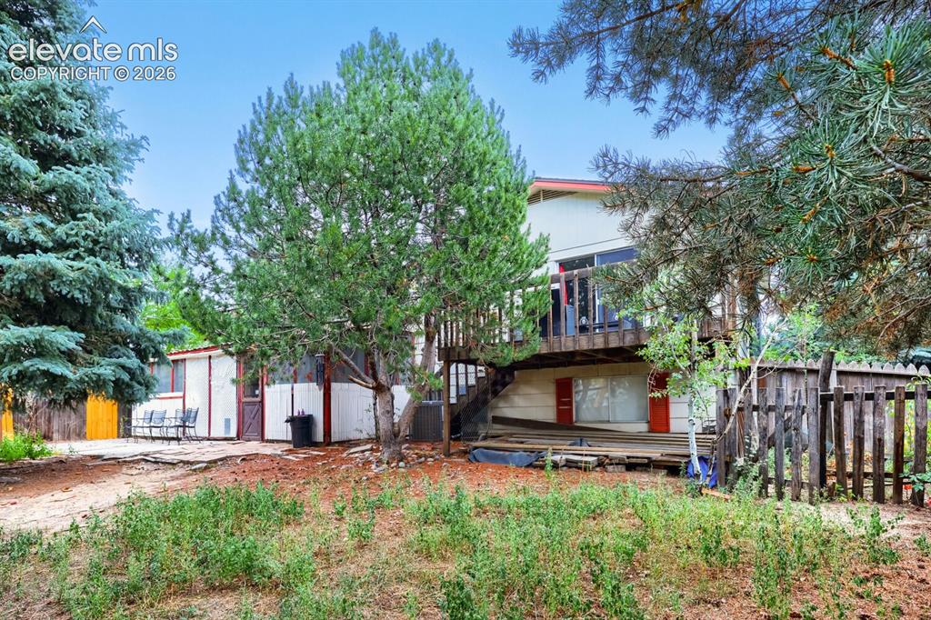 Image 25 of 26: Multi-level exterior with a second-story deck, ground-level patio, and natu