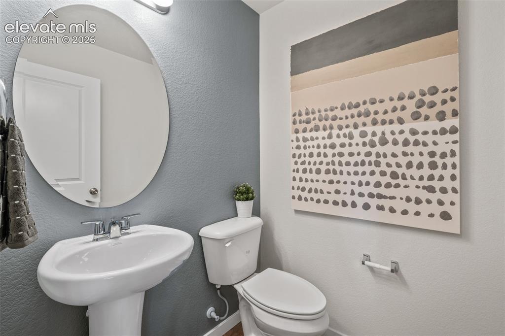 Image 10 of 26: Pedestal sink with a chrome faucet, illuminated by a contemporary oval mirr
