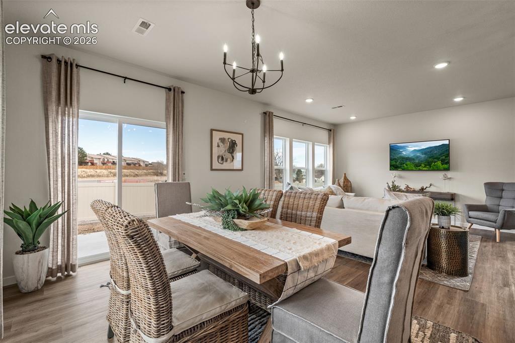 Image 11 of 26: Open-concept living area with wood-finish flooring, recessed lighting, and