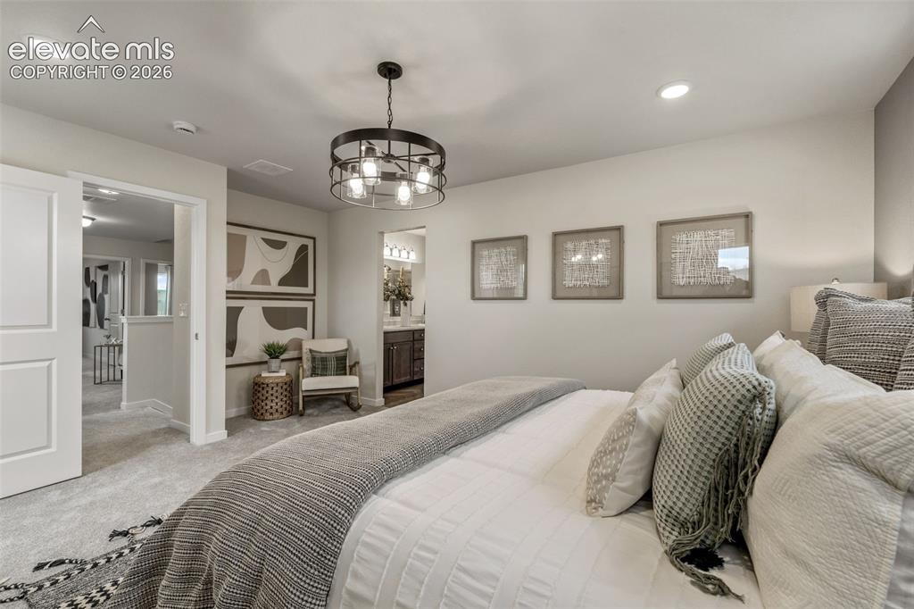 Image 17 of 26: Carpeted flooring, recessed lighting, and a dark metal chandelier with expo
