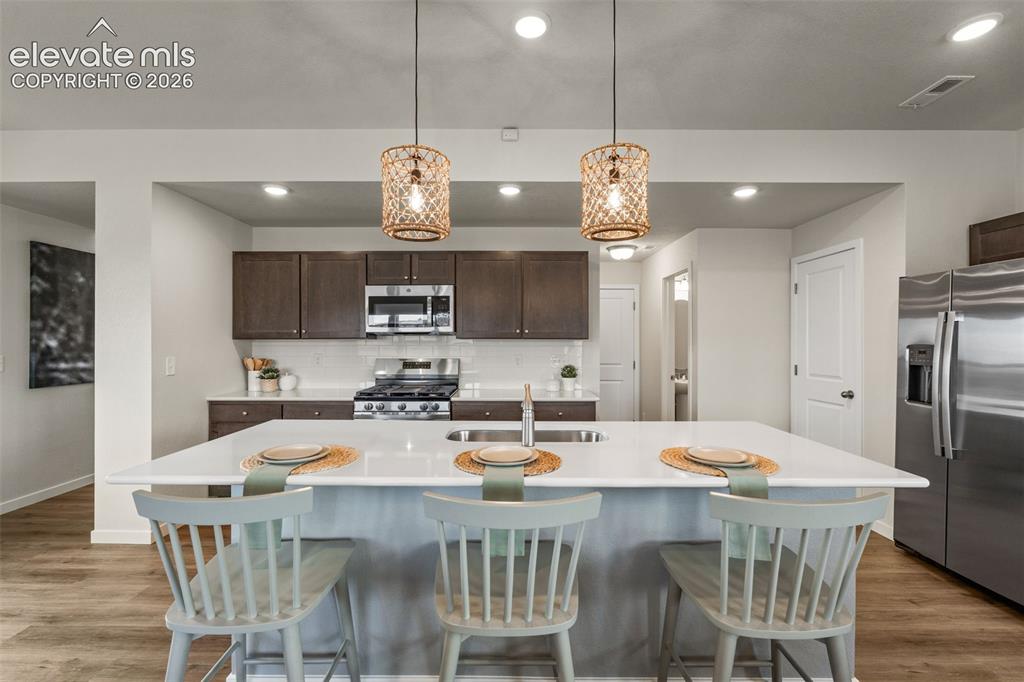 Image 5 of 26: Kitchen featuring a large island, stainless steel appliances, wood-finish f