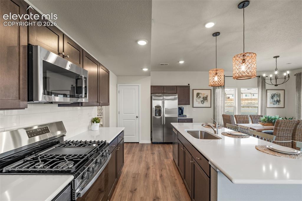 Image 7 of 26: Kitchen featuring stainless steel appliances, dark wood-finish cabinetry, w