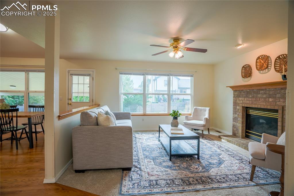 Image 24 of 37: Living room with a brick fireplace, and a ceiling fan