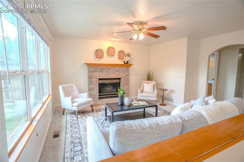 Image 25 of 37: Living room with carpet floors, arched walkways, a fireplace, and a ceiling