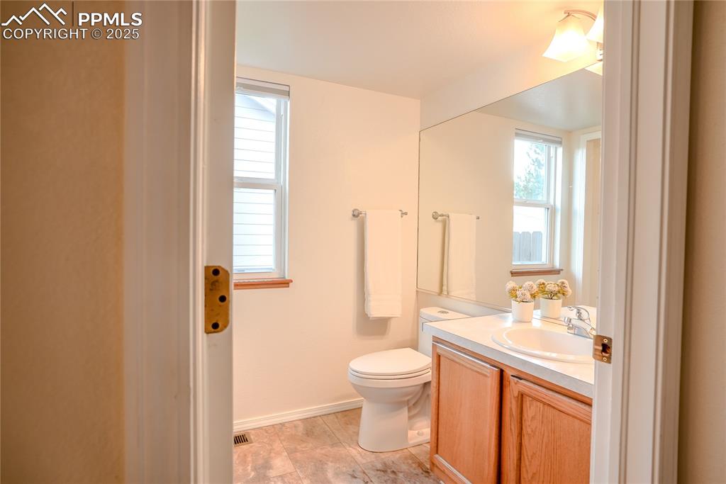 Image 26 of 37: Half bathroom featuring vanity and toilet. Laundry area.
