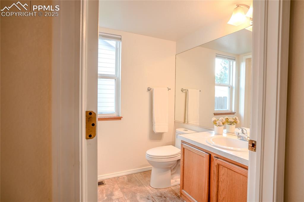 Image 26 of 37: Half bathroom featuring vanity and toilet. Laundry area.