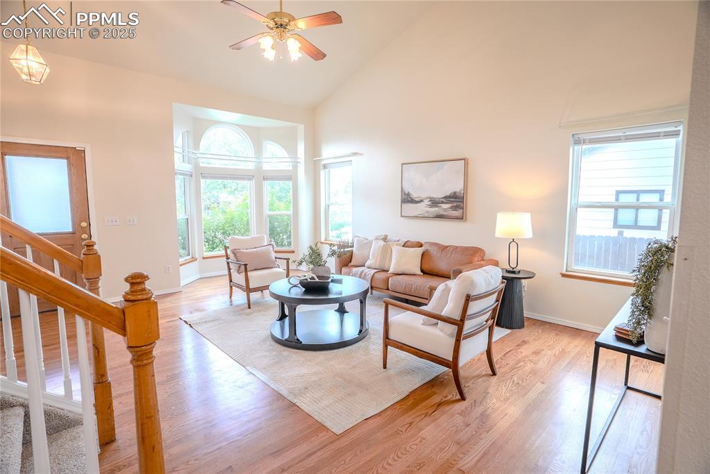 Image 3 of 37: Living room with high vaulted ceiling, wood finished floors, stairs, and a
