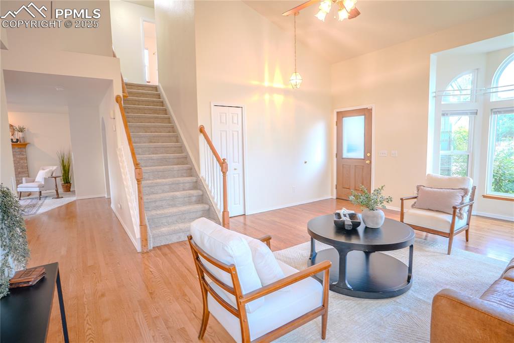 Image 4 of 37: Living room with high vaulted ceiling, wood finished floors, stairs, and ce