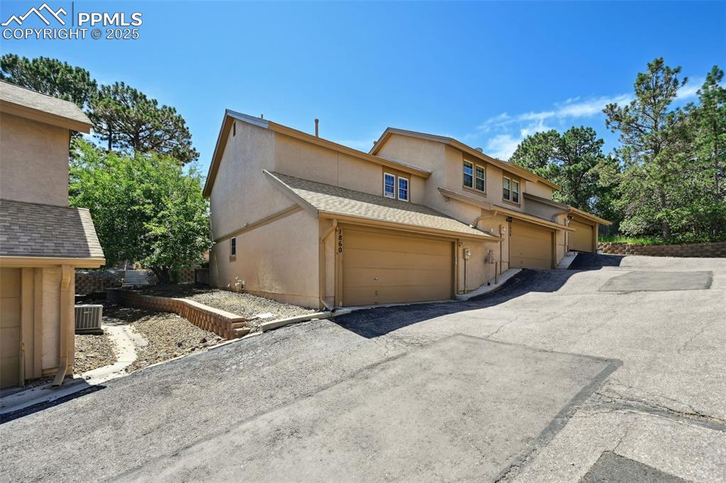 Image 2 of 18: Multi unit property with stucco siding, a garage, and driveway