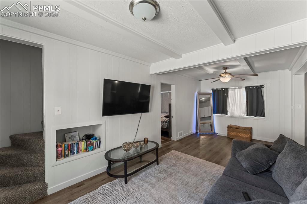 Image 11 of 19: Living area with beam ceiling, a textured ceiling, wood finished floors, wo