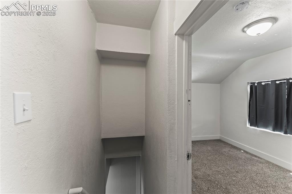 Image 15 of 19: Staircase with a textured ceiling and carpet flooring