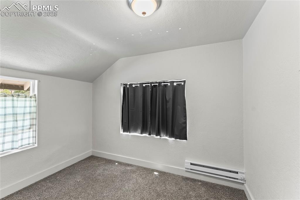 Image 16 of 19: Additional living space featuring a textured ceiling, lofted ceiling, a bas