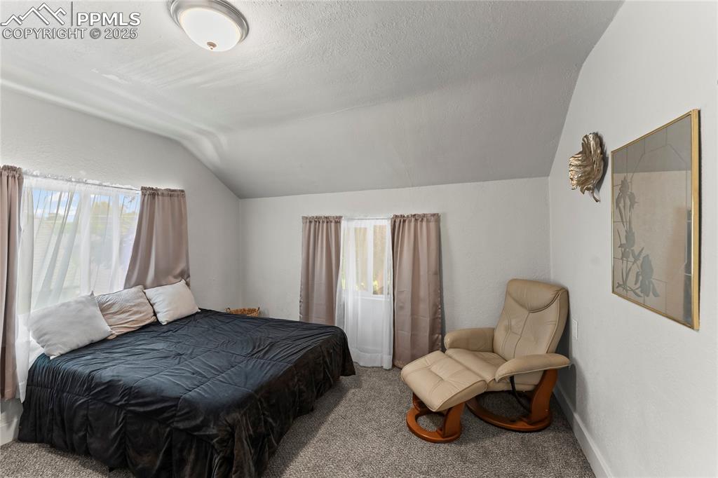 Image 18 of 19: Carpeted bedroom featuring vaulted ceiling and a textured ceiling
