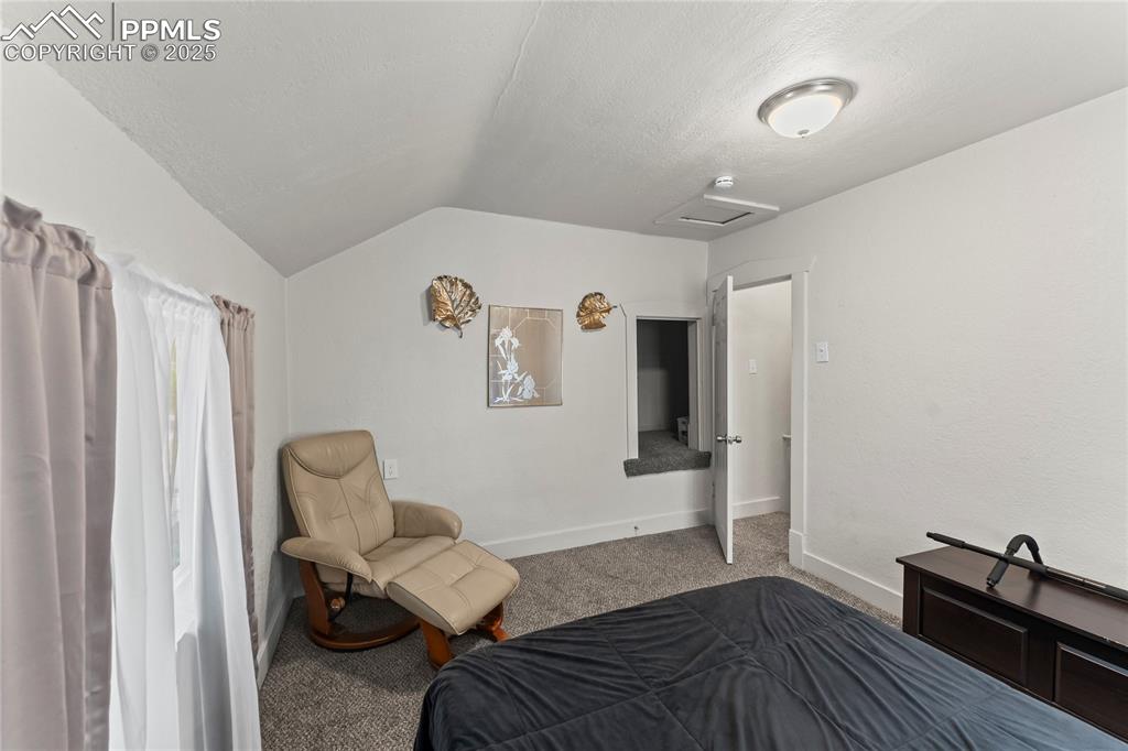 Image 19 of 19: Carpeted bedroom with vaulted ceiling, attic access, and a textured ceiling
