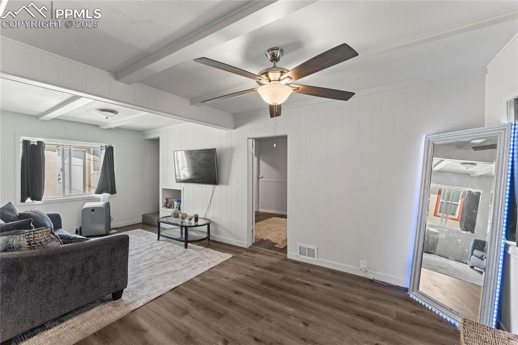 Image 8 of 19: Living room with beamed ceiling, dark wood finished floors, a ceiling fan, 