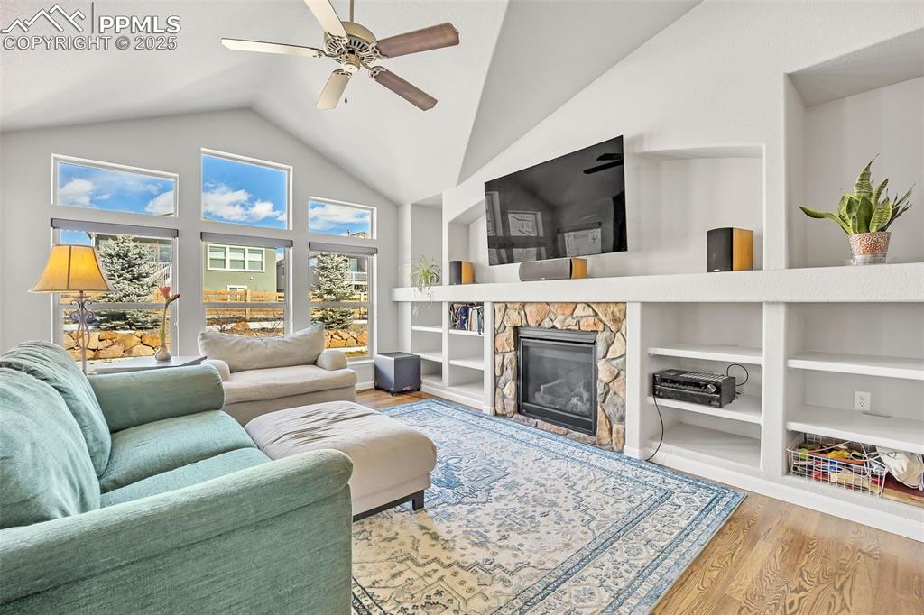Image 11 of 45: Living area with ceiling fan, built in shelves, a fireplace, wood finished