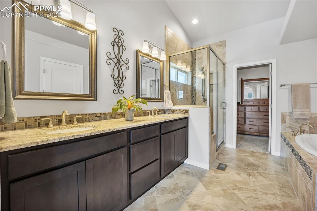 Image 16 of 45: Full bath with lofted ceiling, a garden tub, a sink, double vanity, and a s