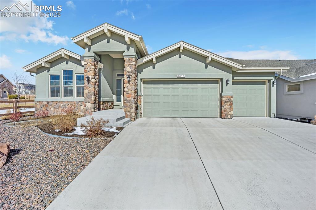 Image 2 of 45: View of front of property with a garage, stone siding, driveway, and stucco