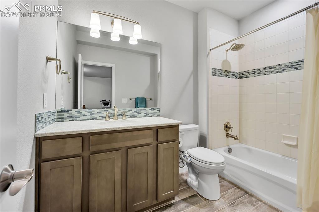 Image 34 of 45: Full bath featuring backsplash, toilet, shower / bath combo, and vanity
