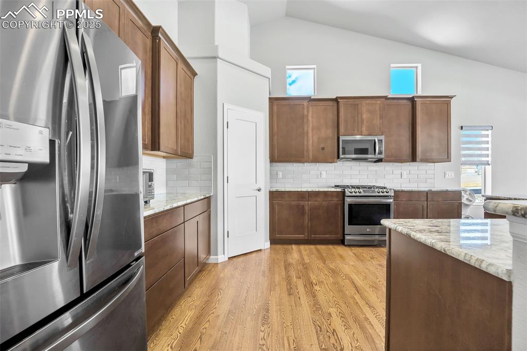 Image 4 of 45: Kitchen featuring tasteful backsplash, light stone countertops, light wood-